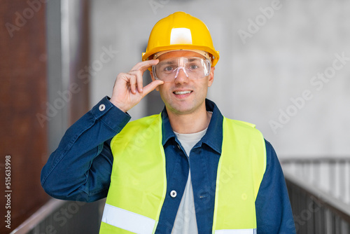 architecture, construction business and building concept - happy smiling male architect in helmet, goggles and safety west at office