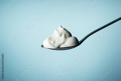 Sour cream in a spoon on a blue background