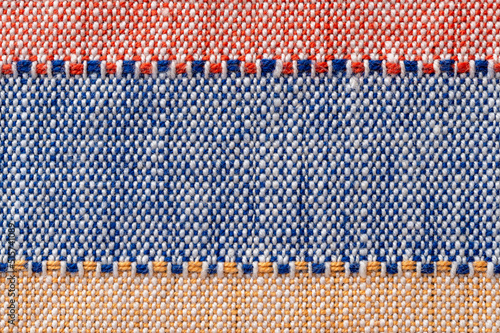 Plain weave fabric macro background. Textile with horizontal strips of red, blue, yellow colors. Detail of cloth texture surface. Weft and warp. Colorful woven fabric for design element.