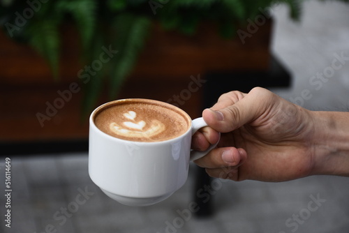 Hand holding hot cup of coffee