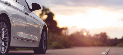 Behind a beautiful white car parked on a road with beautiful sunsets. with space for text.