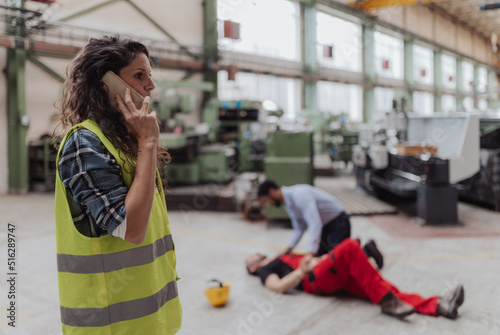 Woman is calling ambulance for her colleague after accident in factory. First aid support on workplace concept.