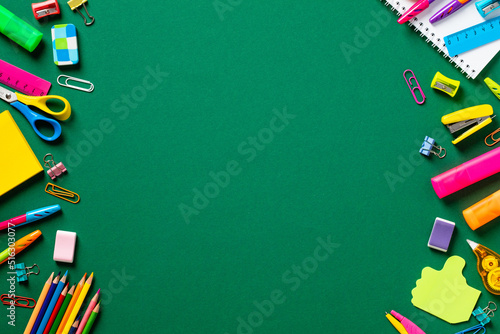 Back to school concept. Frame made of colorful school supplies on green background. Flat lay, top view, copy space.
