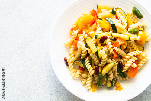 Vegan pasta fusilli with vegetables, zucchini, paprika and grean beans. Meatless vegetarian menu. Top view on white.