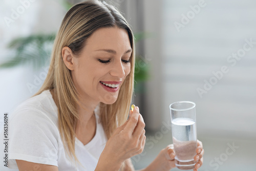 Smiling pretty woman taking pill after waking up, copy space