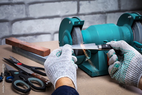 Man sharpening the knife with a electric sharpener. Small business.