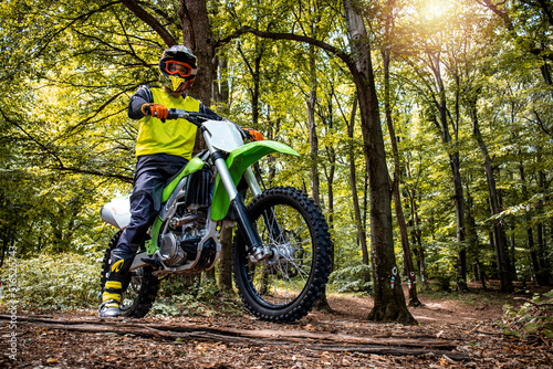 Dirt bike rider enjoying off road ride through the forest and rough terrain.