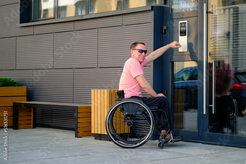 man with disability who uses a wheelchair dials the access code to the apartment on the door of the house