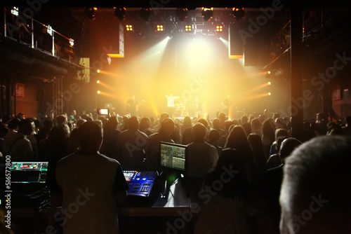 Crowd of spectators in front of the stage at a concert of a popular band in the concert club.