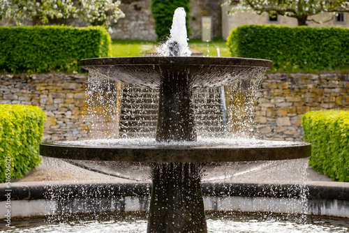 Old fountain in the renovated historic gardens of Dalheim monastery “Kloster Dalheim“ in Lichtenau near Paderborn Germany. Sprinkeling well with perfect symmetry on a sunny springtime day.