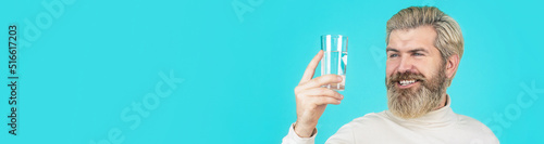 Smiling male holding transparent glass in her hand. Happy beard man drinking water