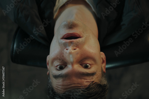 A man snorts cocaine while sitting at his desk in his office and tilts his head back as he gets high. Closeup portrait of a man high on drugs 