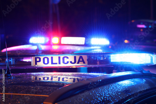 Nocna interwencja alarmowa policji - Sygnalizator błyskowy niebieski na dachu radiowozu policji polskiej w nocy.