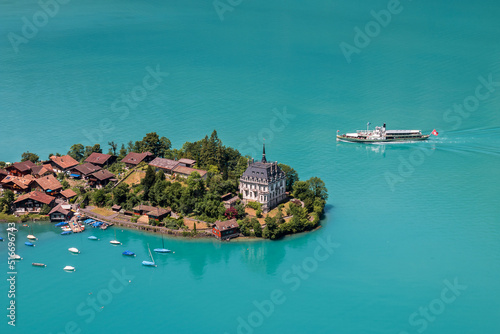 High view over the village of Iseltwald at the turquoise Brienz Lake with a tour ship on the lake, Switzerland.