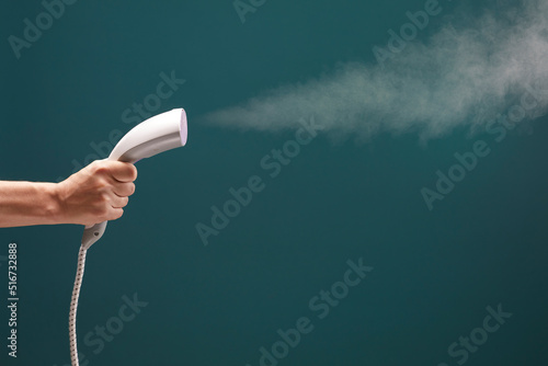 Close up view of male hand with vertical steamer isolated on green background.