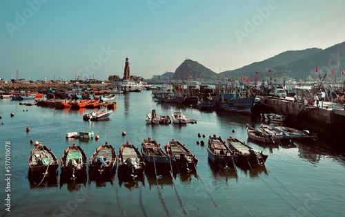Fishing boats in the harbor against the hills and blue sky. Dalian, China.