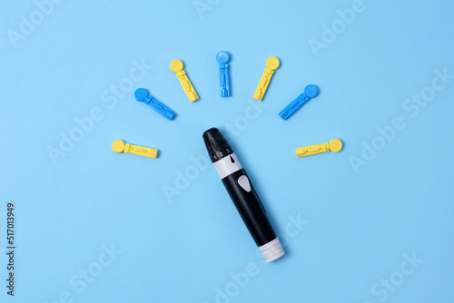Diabetes concept on blue background. An abstract clock made of interchangeable needles and a lancet for blood sugar testing.