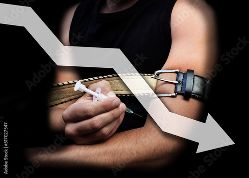 concept of increasing the number of drug addicts or drug trafficking. a man makes himself an injection, tightening his hand with a belt, black background