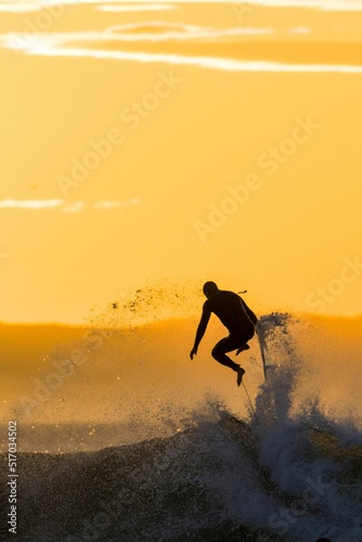 Surfer riding a point break waves and being wipeout during sunset in Jeffreys Bay, South Africa