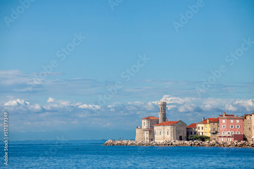 Panorama of Piran, Slovenia, with Adriatic sea in front, with blue water and sky, on a wharf quay, during a sunny summer afternoon. Piran, or Pirano, is a slovenian city on the adriatic sea in istria