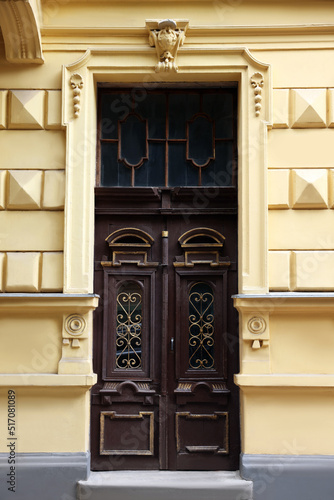 Entrance of house with beautiful wooden door, elegant moldings and transom window