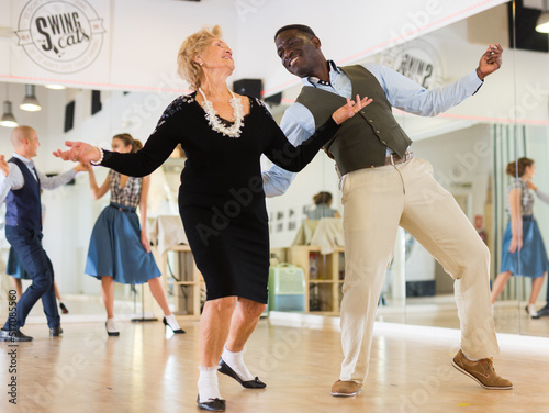 Lady learning to dance lindy hop with man in dance school