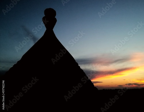 The silhouette of a trullo lies on a blurred sunrise in Puglia, Italy