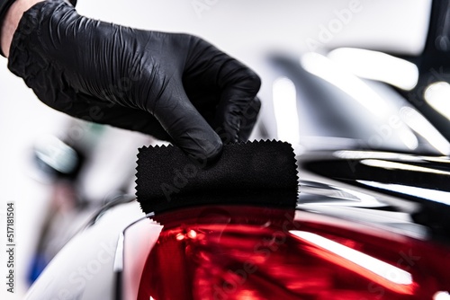 Employee of a car wash or a car detailing studio applies a ceramic coating to the paintwork