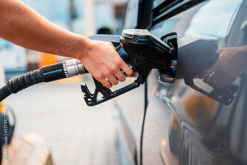 Closeup of woman pumping gasoline fuel in car at gas station. Petrol or gasoline being pumped into a motor. Transport concept