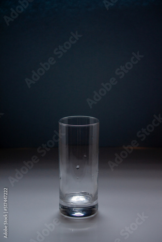 an empty tall glass stands on a blue background