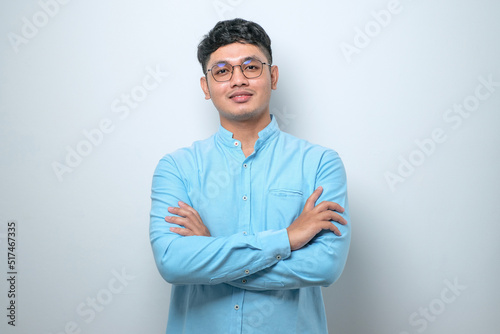 Asian man standing with arms crossed and smiling at camera isolated over white background