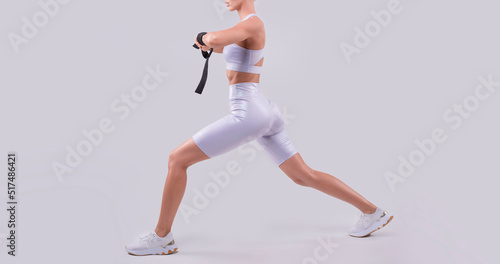 Image of a sports girl who trains with rubber bands in a white studio. Fitness and bodybuilding concept.