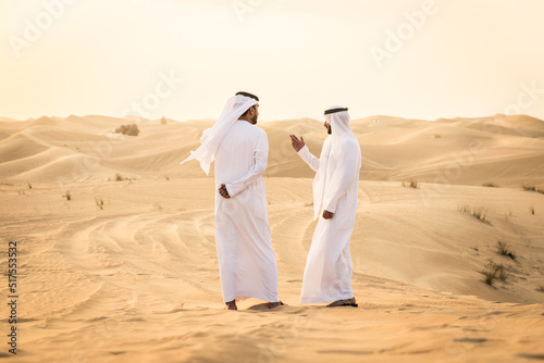 Arabic men in the desert of Dubai wearing traditional emirates clothing