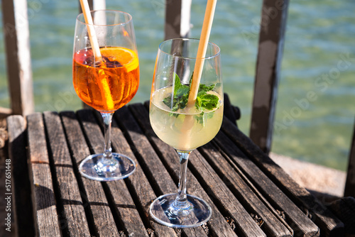 Hugo and Aperol Sprizz together on a wooden table, with the Ammersee in the background