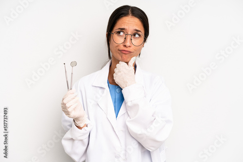 hispanic pretty woman thinking, feeling doubtful and confused. dentist student concept