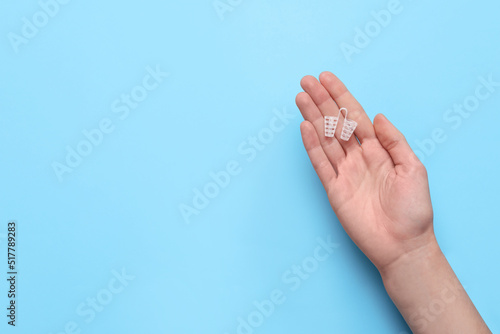 Woman holding anti-snoring device on light blue background, top view. Space for text