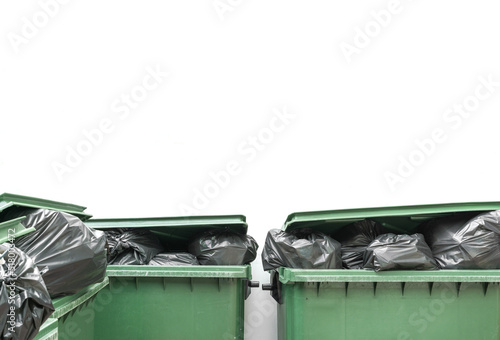 green bin full of garbage bag and white wall background