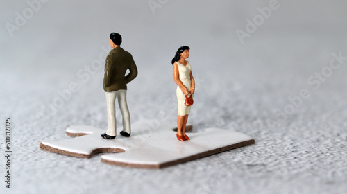 Miniature people standing on puzzle pieces. The concept of gender conflict. 