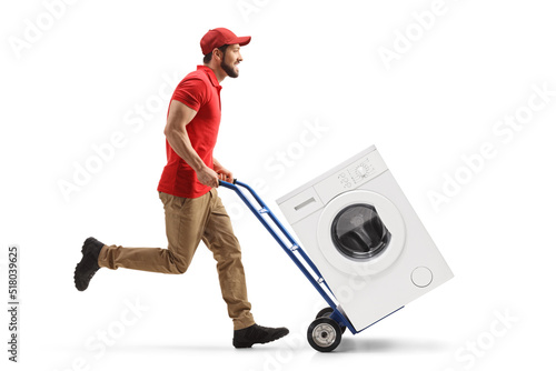 Full length profile shot of a male worker running and pushing a hand-truck with a washing machine