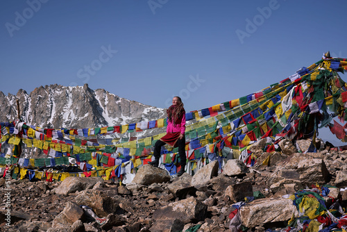 woman standing on top of high pass in Himalayan mountains marked with Buddhist flags
