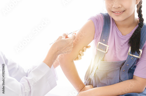 light and blur people, doctor inject vaccine to deltoid muscle of asian girl, children immunization and health care promotion