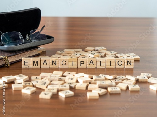 emancipation word or concept represented by wooden letter tiles on a wooden table with glasses and a book