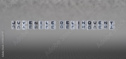 juvenile delinquent word or concept represented by black and white letter cubes on a grey horizon background stretching to infinity