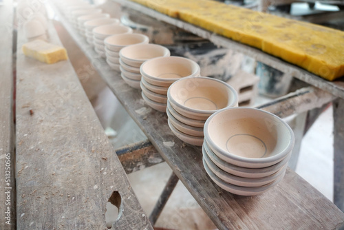 Raw vintage style kaolin cups or China clay cups are arranged in rows on the shelf. How to make the traditional ceramic pottery.