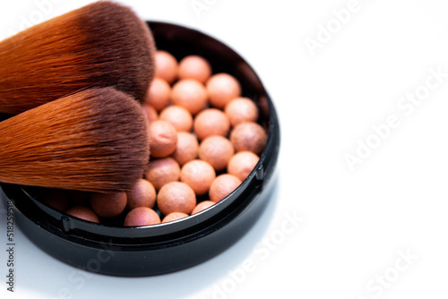 Cosmetic powder balls and makeup brush isolated on white background.
