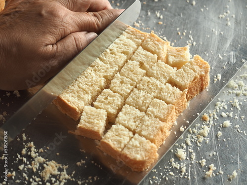 slicing white bread into cubes for making croutons