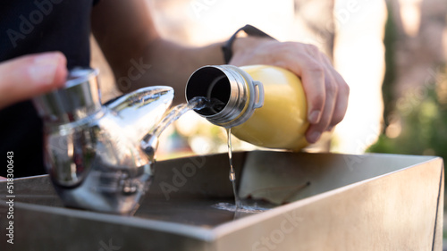 hands refilling a water bottle at the park fountain