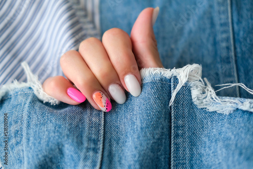 Beautiful female hands with manicure on a denim background. Stylish nail design. Summer manicure with orange and pink pattern on the nails. Copy space.