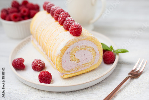 Tasty roll cake, sponge roll, Swiss roll stuffed with cream cheese ,decorated with fresh raspberries. 