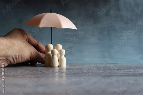 Umbrella and wooden dolls with copy space. Family protection and insurance coverage concept.